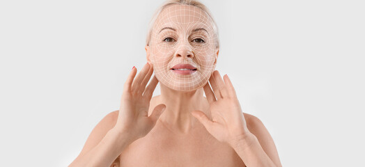 Wall Mural - Mature blonde woman with healthy skin on light background