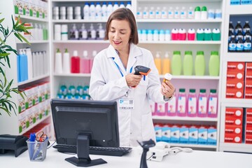 Poster - Middle age woman pharmacist scanning pills bottle at pharmacy