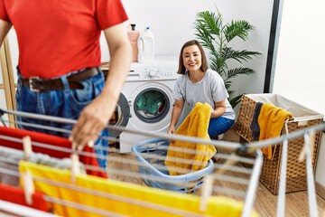 Wall Mural - Middle age man and woman couple smiling confident hanging clothes on clothesline at laundry