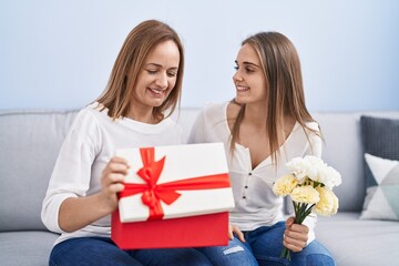 Canvas Print - Two women mother and daughter surprise with birthday gift and flowers at home