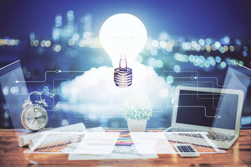 Poster - Computer on desktop in office with bulb icon hologram. Double exposure. Concept of idea.