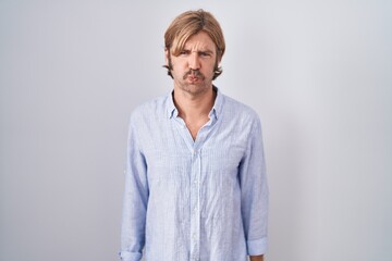 Canvas Print - Caucasian man with mustache standing over white background puffing cheeks with funny face. mouth inflated with air, crazy expression.