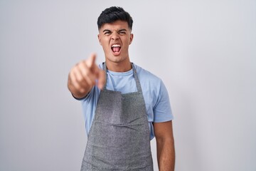 Sticker - Hispanic young man wearing apron over white background pointing displeased and frustrated to the camera, angry and furious with you