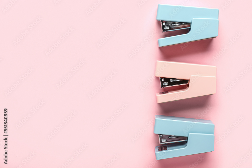 Office staplers on pink background
