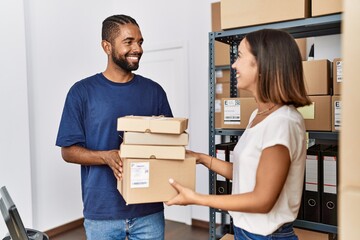 Canvas Print - Man and woman business partners smiling confident holding packages at storehouse