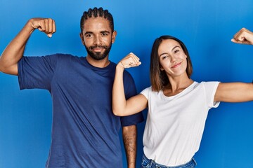 Canvas Print - Young hispanic couple standing together showing arms muscles smiling proud. fitness concept.