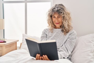 Sticker - Middle age woman reading book sitting on bed at bedroom