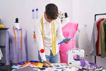 Poster - Young hispanic teenager tailor using touchpad drawing clothing design at tailor shop