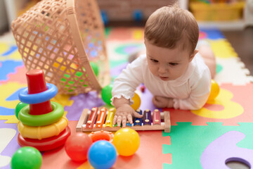 Wall Mural - Adorable toddler touching xylophone lying on floor at kindergarten