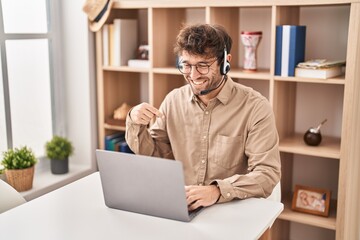 Wall Mural - Hispanic young man wearing call center agent headset pointing finger to one self smiling happy and proud