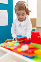 Sticker - Adorable caucasian girl playing with construction blocks standing at kindergarten