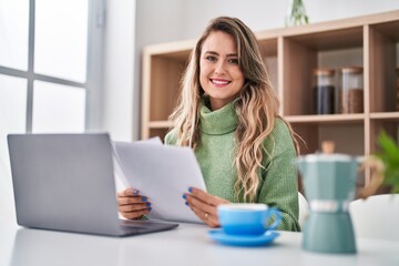 Poster - Young woman reading document using laptop at home
