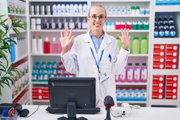 Sticker - Young caucasian woman working at pharmacy drugstore showing and pointing up with fingers number nine while smiling confident and happy.