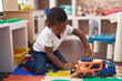 © Krakenimages.com - African american boy playing with cars and truck toy sitting on floor at kindergarten