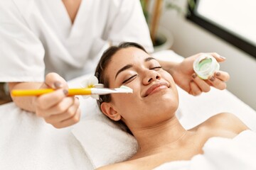 Poster - Young latin woman relaxed having skin face aloe vera treatment at beauty center