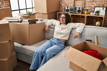 Poster - Young hispanic woman smiling confident relaxed sitting o sofa at new home