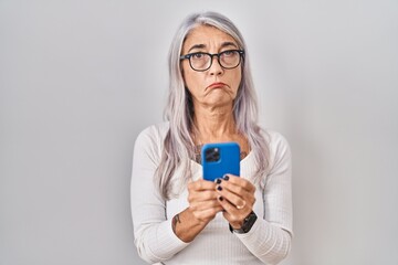 Sticker - Middle age woman with grey hair using smartphone typing message depressed and worry for distress, crying angry and afraid. sad expression.