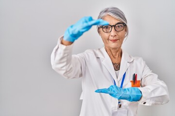 Poster - Middle age woman with grey hair wearing scientist robe gesturing with hands showing big and large size sign, measure symbol. smiling looking at the camera. measuring concept.