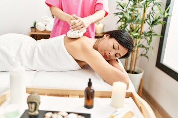 Poster - Middle age hispanic woman having back massage using thai bags at beauty center