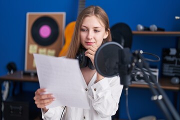 Poster - Young caucasian woman artist reading song with doubt expression at music studio