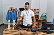 © Krakenimages.com - Young hispanic man shopkeeper smiling confident cleaning dust at clothing store