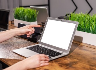 Poster - Finger pointing at blank white screen mockup of laptop computer in office interior