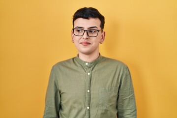 Poster - Non binary person standing over yellow background smiling looking to the side and staring away thinking.