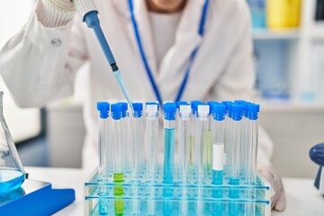 Canvas Print - Young hispanic woman wearing scientist uniform using pipette at laboratory