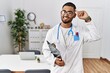 © Krakenimages.com - Young indian man wearing doctor uniform and stethoscope smiling pointing to head with one finger, great idea or thought, good memory