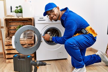 Canvas Print - Young arab man wearing technician uniform repairing washing machine at laundry room