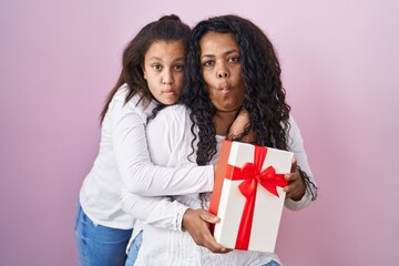 Sticker - Mother and young daughter holding with presents making fish face with mouth and squinting eyes, crazy and comical.