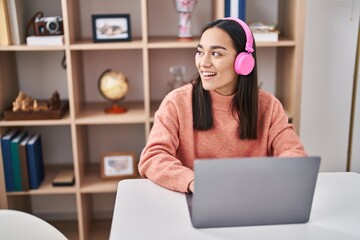 Sticker - Young hispanic woman using laptop and headphones sitting on table at home