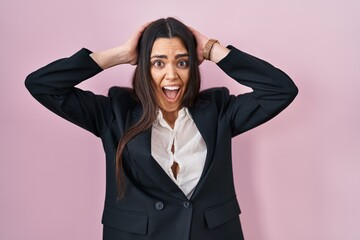 Canvas Print - Young brunette woman wearing business style over pink background crazy and scared with hands on head, afraid and surprised of shock with open mouth