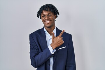 Canvas Print - Young african man with dreadlocks wearing business jacket over white background cheerful with a smile on face pointing with hand and finger up to the side with happy and natural expression