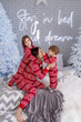© Olena - People in same family look red pajamas playing at home in christmas day. Happy funny kids daughter, son with mother spend time, enjoying being together in decorated winter bedroom. New Year holidays