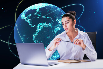 Aufkleber - Thoughtful young european businesswoman sitting at desk with laptop and creative glowing globe hologram on dark background. Technology, metaverse and digital map concept.