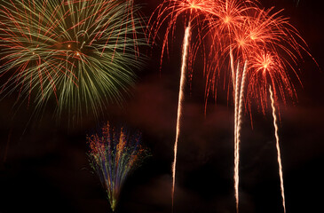 three different types of fireworks in various colors, exploding in the sky