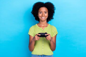 Sticker - Photo of small cute cheerful positive nice schoolgirl teenager wear green t-shirt smiling hold joystick player playstation chill isolated on blue color background