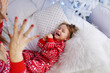 © Olena - People in same family look red pajamas, kidding at home christmas day. Happy funny kid child son with mother spend time together, enjoying, fool around in bed in bedroom. New Year holidays. Homeliness
