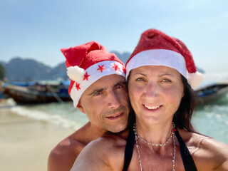 Poster - Family Tropical Christmas. Caucasian couple wearing Christmas Hats on a beautiful beach