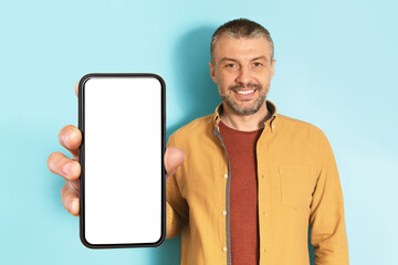 Poster - App advertisement. Happy mature man showing big white empty smartphone screen, recommending website or app, mock up