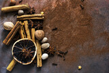 Fototapeta Tulipany - Christmas spices. Christmas composition with cinnamon sticks; anise stars, nutmeg, cloves, hazelnut and dried orange slices on dark background. Copy space for your text. Rustic vibe.