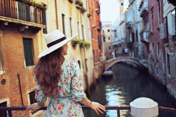 Seen from behind trendy woman in floral dress sightseeing