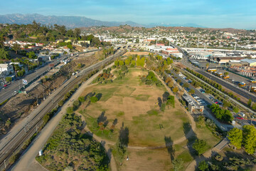 aerial shot gorgeous autumn landscape at Los Angeles State Historic Park surrounded by streets with cars driving and hillsides covered homes with blue sky and clouds in Los Angeles California