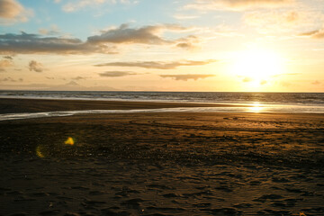 Poster - Beach in silhouette as sunsets on distant horizon over ocean.