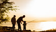 © Andrii Lysenko - Family dad and two sons are fishing at sunset, silhouette of a man and two boys.