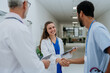 © Halfpoint - Doctors greetings and shaking hands at hospital corridor.