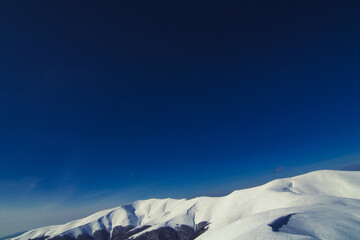 Deep blue sky above mountain peak landscape photo. Beautiful nature scenery photography with snow on background. Idyllic scene. High quality picture for wallpaper, travel blog, magazine, article