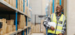© Jacob Lund - Happy warehouse picker looking away with a smile, man stands in a logistics centre with a voice picking headset and a helmet