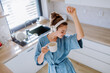 Young woman listening music and enjoying cup of coffee at morning, in her kitchen.